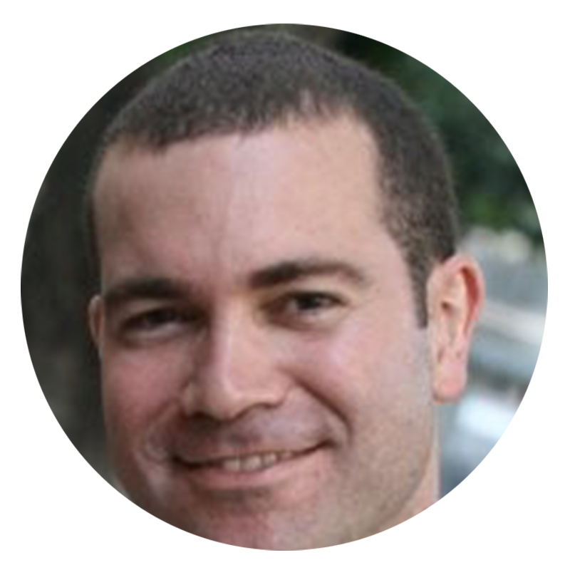 Man smiling with short hair and stubble.