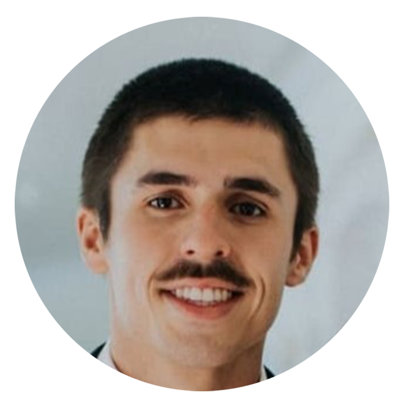 Man with a mustache smiling in a suit.